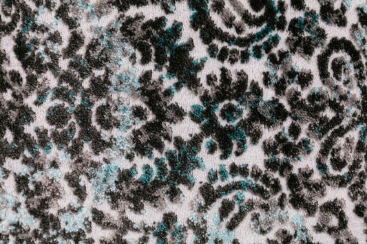 Close-up of grey rug texture with black, white, and teal ornamental details