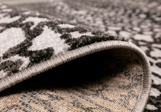 Abstract grey rug edge with braided border and visible low-pile texture