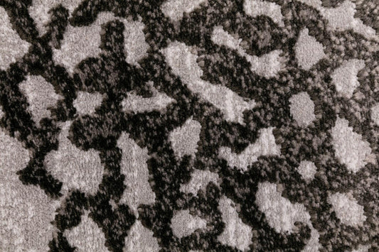 Textured area rug surface with dark background and irregular light grey shapes