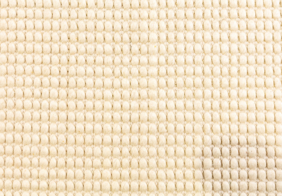 Cream wool rug surface with dense textured looped weave pattern