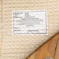 Cream wool rug corner with woven pile and small fabric label tag on underside
