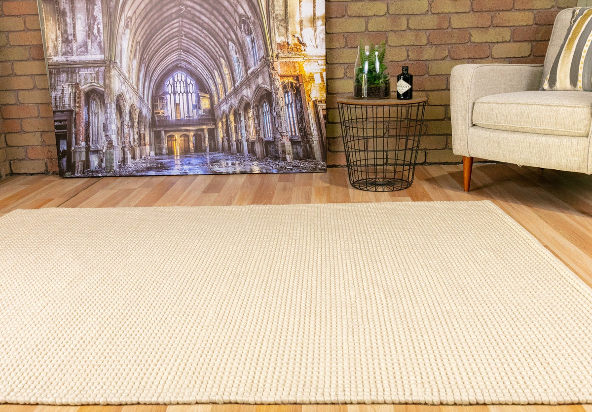 Cream wool rug with textured looped weave, rectangular rug on wood floor