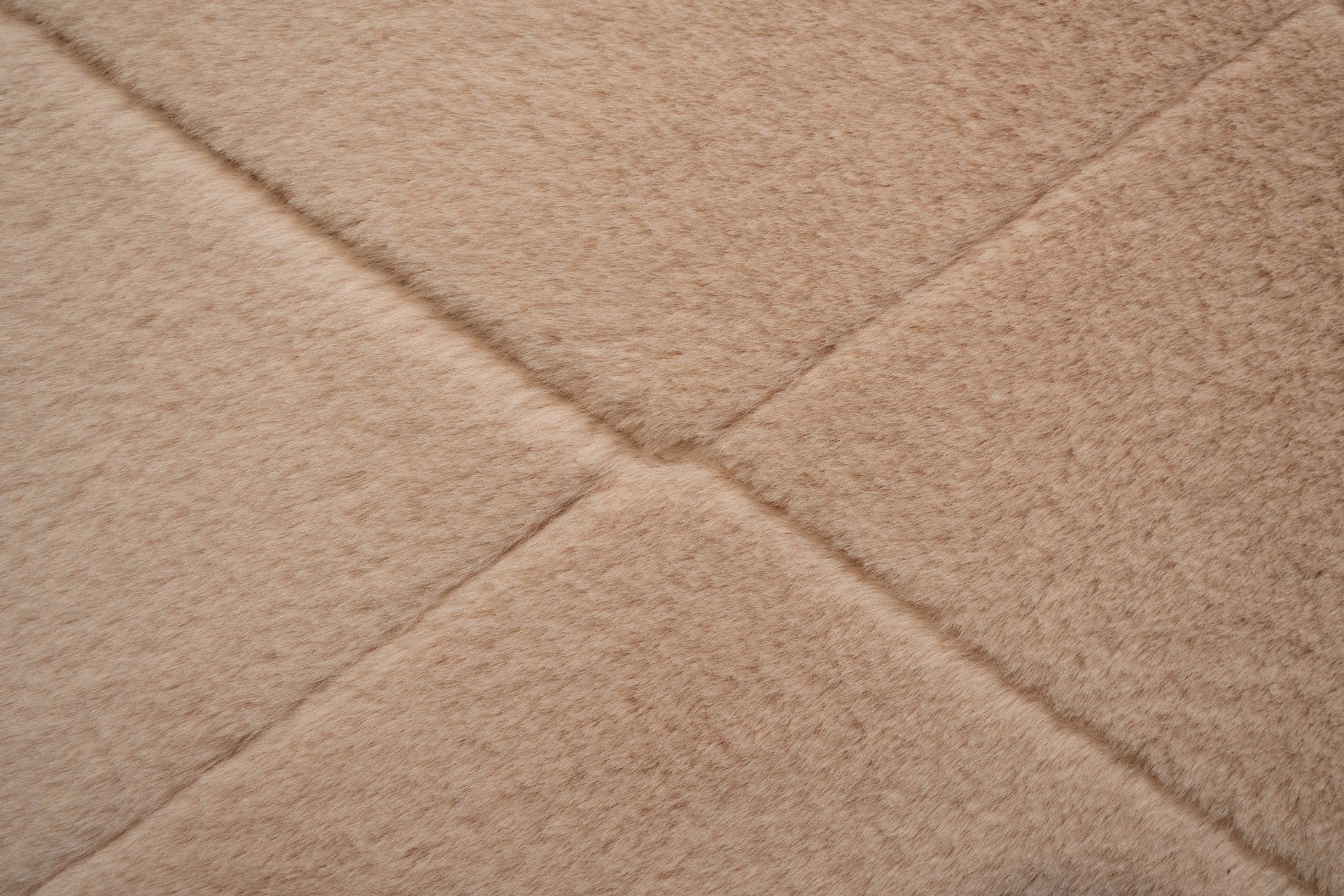 Soft pink shag rug close-up with diamond texture and stitched seam