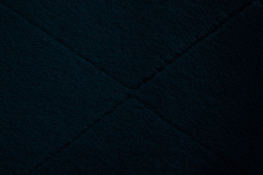 Close-up of dark navy shag rug texture with dense long fibers