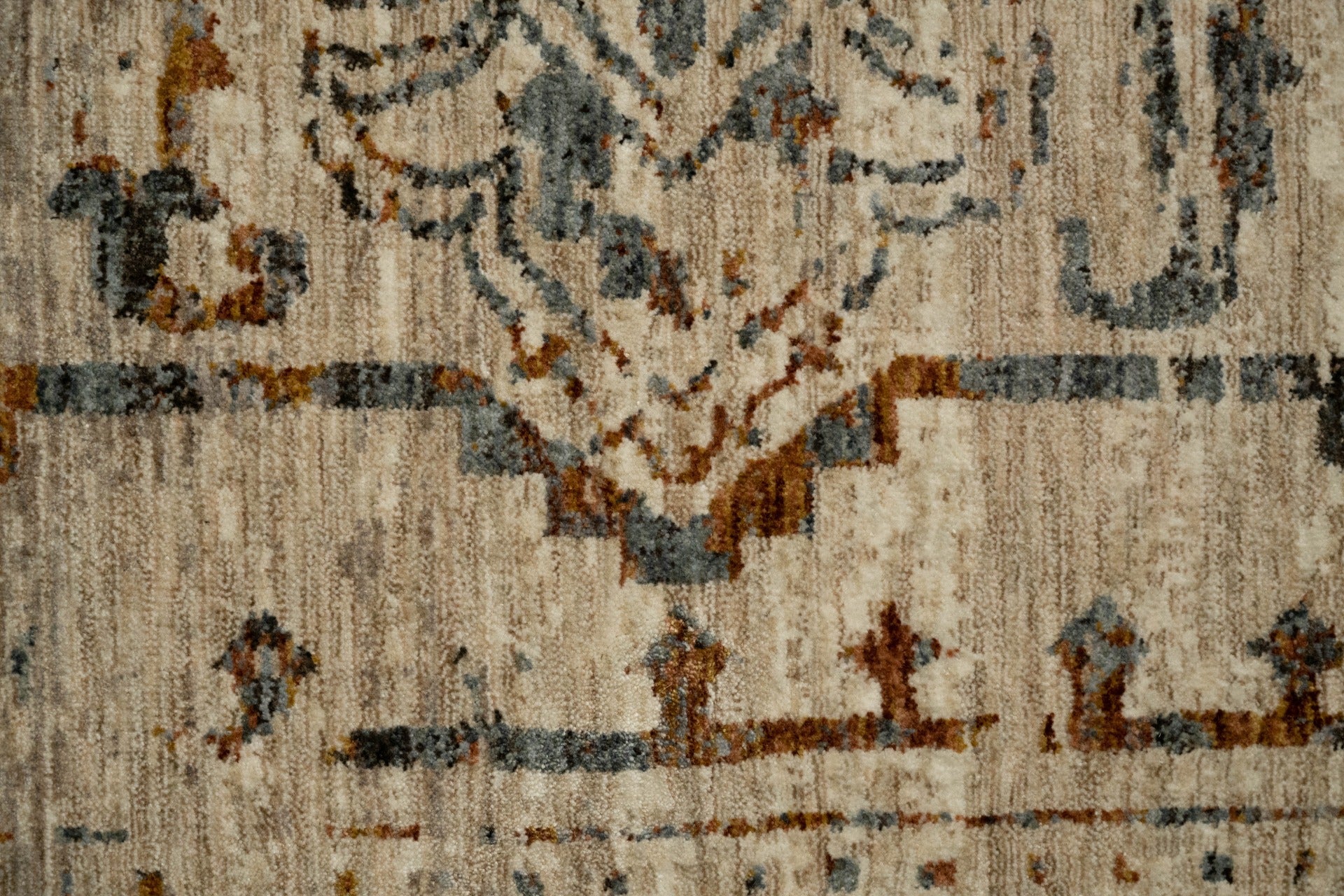 Close-up of distressed area rug pattern with light base, blue and rust accents