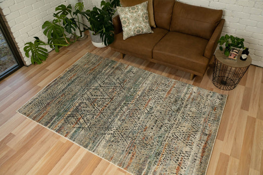 Geometric area rug in beige and gray with muted orange and blue accents, distressed texture