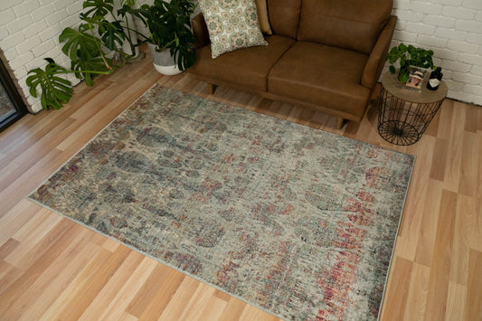 Distressed rectangular area rug in teal, gray, beige and rust with ornate pattern
